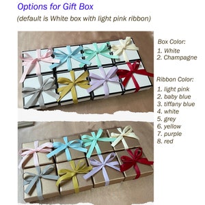 May include: A selection of gift boxes with different colored ribbons. The boxes are white or champagne colored. The ribbons are light pink, baby blue, tiffany blue, white, grey, yellow, purple, and red. The text on the image reads "Options for Gift Box (default is White box with light pink ribbon)" and "Box Color: 1. White 2. Champagne" and "Ribbon Color: 1. light pink 2. baby blue 3. tiffany blue 4. white 5. grey 6. yellow 7. purple 8. red".