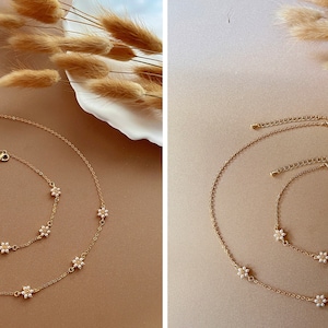 Peut inclure: Un ensemble de deux colliers en or avec de d&eacute;licats pendentifs en forme de fleurs. Le collier le plus long a cinq pendentifs et le collier le plus court en a quatre.