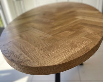 May include: A wooden oval table with a herringbone pattern top and black metal legs.