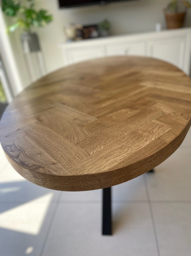 May include: A wooden oval table with a herringbone pattern top and black metal legs.