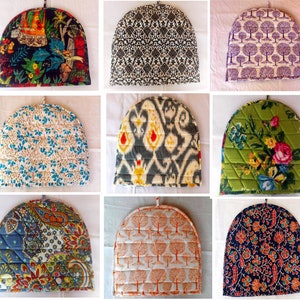 Peut inclure: Collection de chauffe-théières matelassées avec divers motifs. Les motifs incluent des fleurs, des cachemires et des motifs géométriques dans des couleurs comme le bleu, le vert, l'orange et le noir. Chaque chauffe-théière a une boucle pour suspendre et est matelassée.