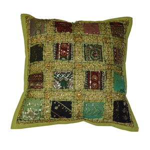 May include: A green square cushion with a patchwork design. The cushion is made of different fabrics and colours, including green, red, brown, and gold. The cushion is decorated with sequins and embroidery.