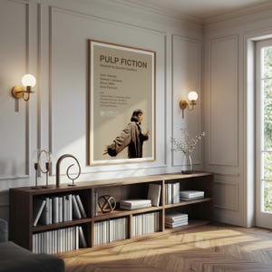 K&ouml;nnte beinhalten: Ein gerahmtes "Pulp Fiction"-Filmplakat h&auml;ngt &uuml;ber einem dunklen Holzregal voller B&uuml;cher. Das Plakat zeigt den Filmtitel und die Besetzung, mit einem Bild von Uma Thurman. Zwei goldene Wandleuchten flankieren das Plakat.