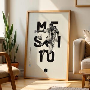 May include: Framed poster featuring a black and white image of a soccer player in action, kicking a ball. The word "MESSI" is displayed in large, bold, black letters. The player is wearing a soccer uniform with the number 10. The poster is in a wooden frame.