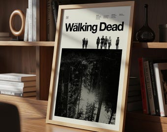 May include: A framed poster with the title "The Walking Dead" in black. The poster shows a black and white forest scene and a group of figures. The frame is made of light-coloured wood.
