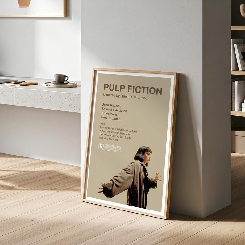 K&ouml;nnte beinhalten: Ein gerahmtes Filmplakat f&uuml;r "Pulp Fiction" mit einem Holzrahmen. Das Poster zeigt den Filmtitel, den Regisseur und die Besetzung, darunter John Travolta und Uma Thurman. Eine Frau in einem Mantel ist ebenfalls abgebildet.