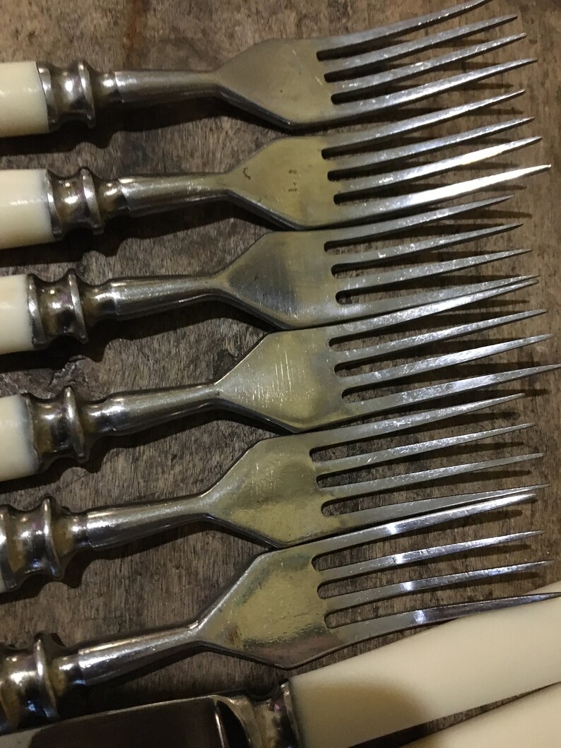 May include: Set of six silver forks with ivory handles. The forks have a traditional design with a rounded handle and a pointed end.