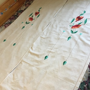Pode incluir: Duas fronhas de linho branco com desenhos florais bordados em vermelho e verde. As fronhas têm um design simples e elegante.
