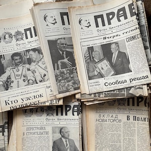 Peut inclure: Une pile de journaux soviétiques d'époque, avec le titre "Pravda" et le texte "Organ Centralnogo" en écriture cyrillique. Les journaux sont imprimés en noir et blanc et ont un aspect usé et vieilli.