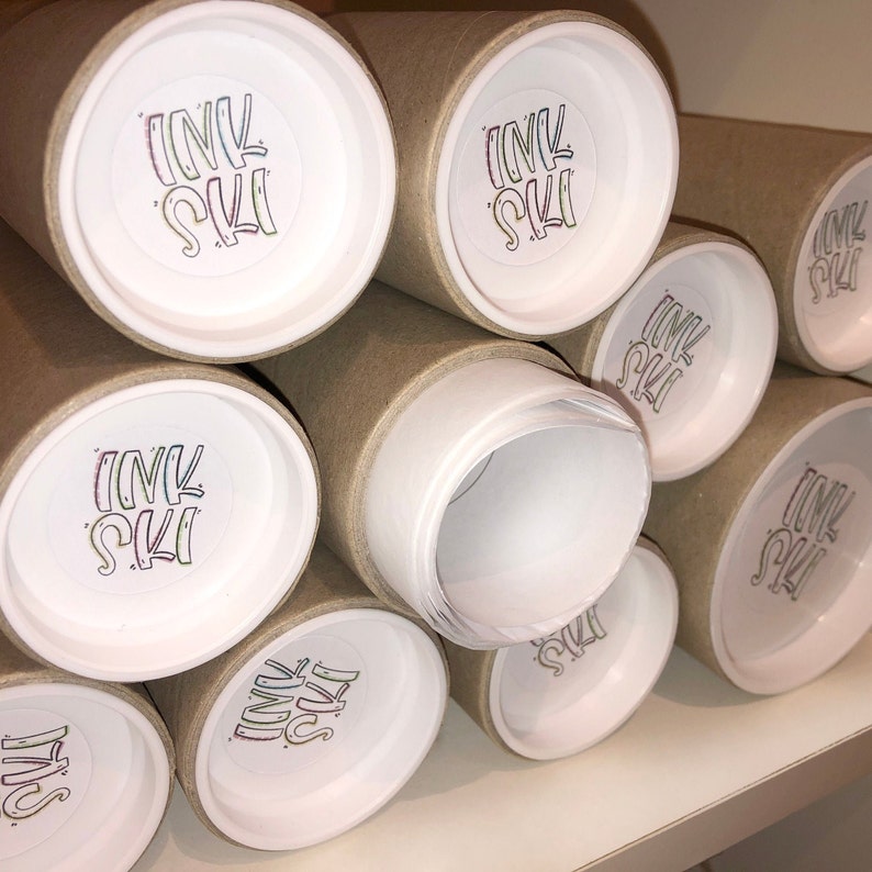 May include: A stack of brown cardboard tubes with white end caps. Each end cap has a colorful sticker with the text "INK SKI" on it.