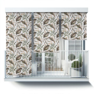 May include: White balcony blinds with a tropical leaf pattern. The blinds are partially rolled up, revealing a view of a balcony with furniture and plants.