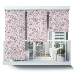 May include: Three white window shades with a pink floral pattern are pulled down to cover the windows of a balcony. The balcony has a white railing and a white floor. There is a white couch and a table with chairs on the balcony.