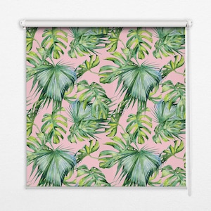 以下が含まれることがあります： ピンクのローラーブラインドに、熱帯の葉の模様が描かれています。葉は緑色で、水彩画のような効果があります。