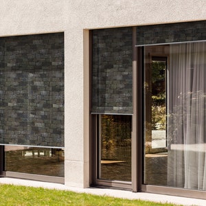 May include: Two windows with black framed glass panes. The windows have retractable shades with a stone pattern. The shades are partially pulled down.