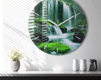 May include: Round glass clock with a waterfall and green foliage image. The clock has white hands and black numbers.