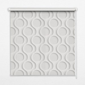 May include: A white roller blind featuring a repeating pattern of interconnected circles. The design consists of overlapping, wavy lines with circular cutouts, creating a textured, three-dimensional effect. The blind is mounted on a white roller mechanism.