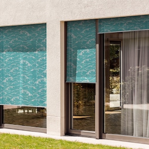 May include: Two windows with teal blue patterned roller shades. The shades have a white wave design. The windows are on a white building with a green lawn in front.