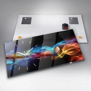 Może przedstawiać: Nowoczesny zegar ścienny z czarnym tłem i abstrakcyjnym wzorem dymu w kolorach. Zegar ma białe wskazówki i srebrną ramkę.