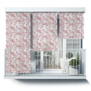 May include: White balcony with three sheer window shades featuring a pink floral pattern. The shades are pulled down and the balcony is empty.