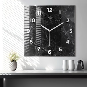 May include: A black and white marble clock with white numbers and hands. The clock is square and has a glass face.