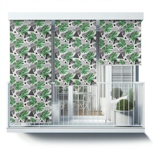 May include: A set of three white window shades with a black and green tropical leaf pattern. The shades are pulled down to cover the windows of a balcony.