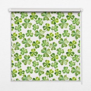 以下が含まれることがあります： 緑のクローバー柄の白いローラーシェード。クローバーは水彩画風で、薄い緑と濃い緑の色をしています。