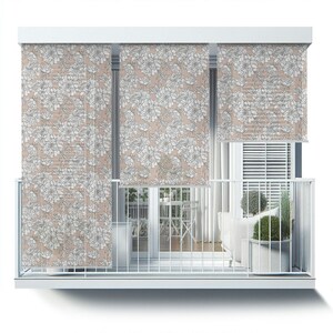 May include: A balcony with white railings and a floral patterned window shade. The shade is a light pink color with white flowers. The balcony has a white couch, a table and chairs, and a potted plant.