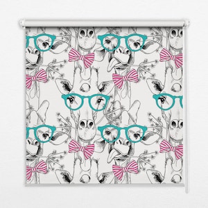 以下が含まれることがあります： キリンのイラストが繰り返されるロールスクリーン。各キリンは、ターコイズ色のメガネとピンクのストライプの蝶ネクタイを着用しています。背景は薄いクリーム色で、デザインは白黒です。