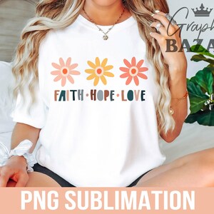 May include: White t-shirt with a graphic of three colorful flowers and the text "Faith Hope Love".