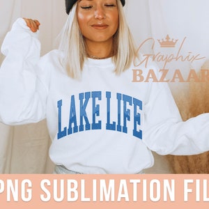 May include: White sweatshirt with blue text that reads "Lake Life" in a varsity style font. The sweatshirt is being modeled by a person wearing a black beanie.