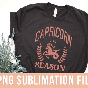 K&ouml;nnte beinhalten: Schwarzes T-Shirt mit einer braunen Grafik eines Steinbock-Sternzeichen und dem Text "Steinbock-Saison".