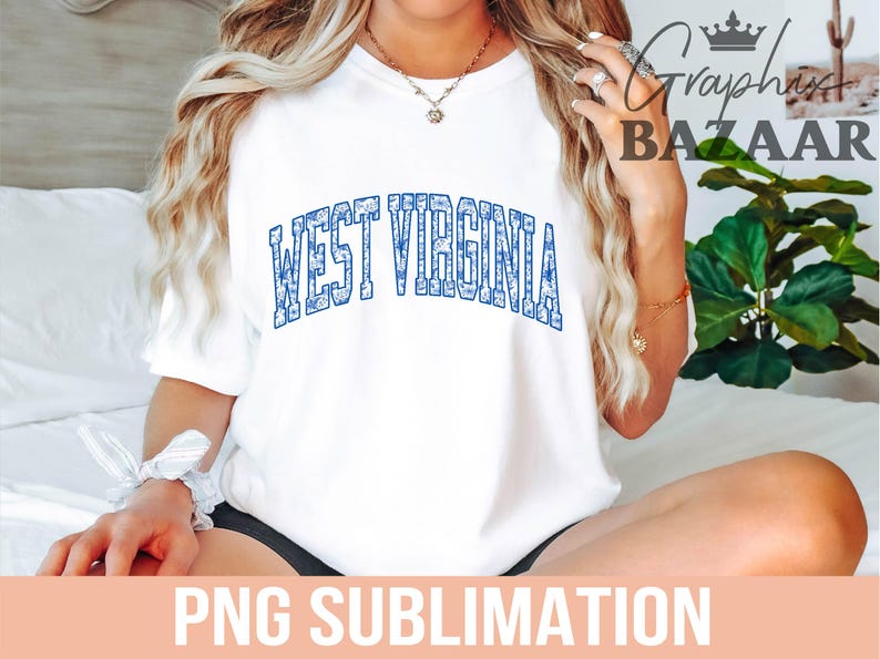 May include: White t-shirt with a blue and white patterned design that says "West Virginia" in a collegiate font.