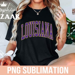 Puede incluir: Camiseta negra con la palabra "LOUISIANA" en letras de bloque moradas con contorno dorado. El texto "PNG SUBLIMATION" est&aacute; en la parte inferior de la imagen. La camiseta la lleva una persona.