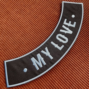 May include: Black and white motorcycle patch with white stitching. The patch is curved and says "MY LOVE."