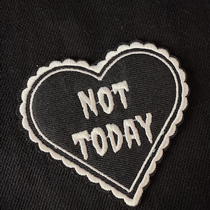 May include: Black heart-shaped patch with white stitching and the text "NOT TODAY" in white.