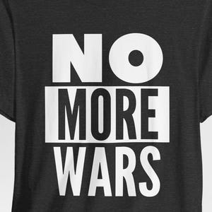 May include: Dark gray t-shirt with the white text "NO MORE WARS" in a bold, sans-serif font. The text is centered on the shirt, with the words stacked vertically. The shirt has short sleeves and a crew neck.