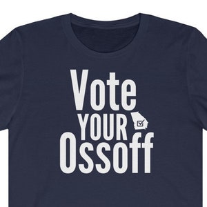 Op de afbeelding: Een marineblauw t-shirt met witte tekst die "Vote Your Ossoff" luidt en een witte omtrek van de staat Georgia met een vinkje erin.