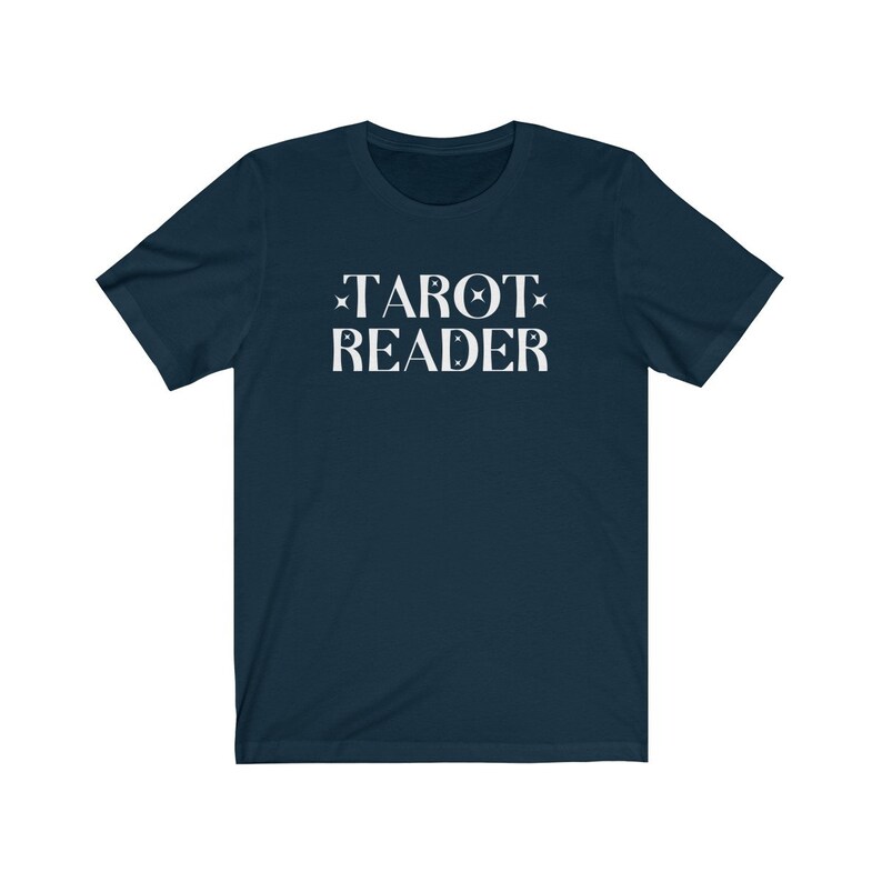 Op de afbeelding: Marineblauw T-shirt met de witte tekst "TAROT READER" in een schreeflettertype. De tekst is gecentreerd en bevat steraccenten. Het shirt heeft korte mouwen en een ronde hals.