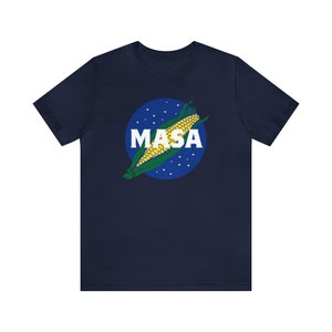 May include: A navy blue t-shirt with a graphic of a corn cob in a blue circle with white stars and the word "MASA" in white letters.
