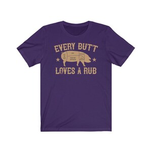May include: Purple short-sleeved t-shirt with a brown graphic of a pig with a butcher diagram and the text "Every Butt Loves A Rub".