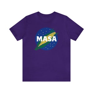 May include: Purple t-shirt with a white circle and a corn cob graphic. The circle has white dots and the text "MASA" in white letters.