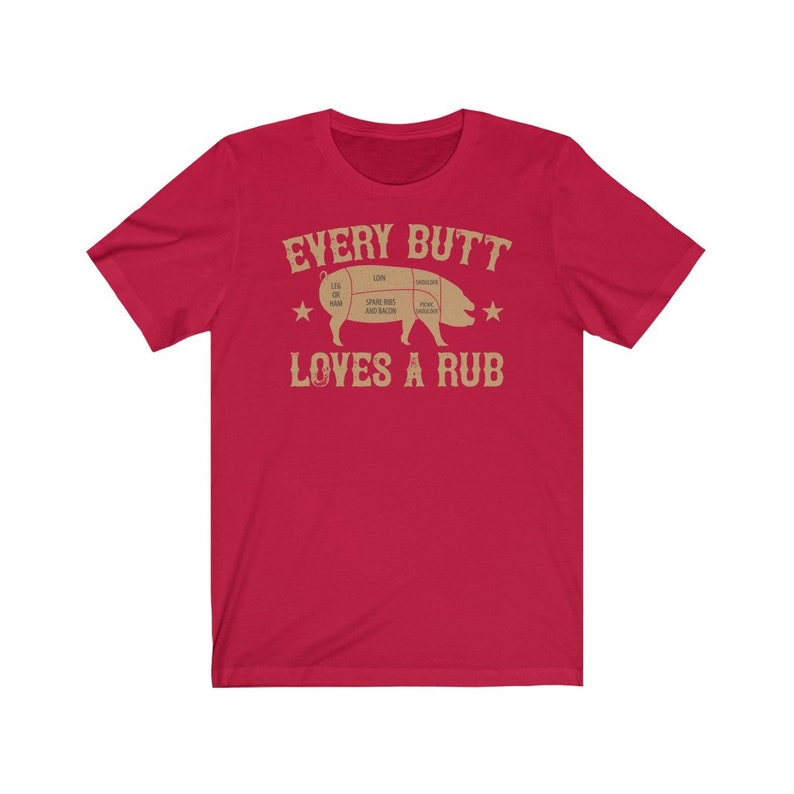 May include: Red short-sleeved t-shirt with a tan pig illustration and the text "EVERY BUTT LOVES A RUB".