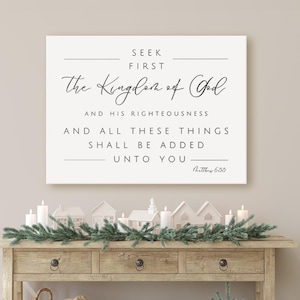 May include: A wooden console table with a framed sign that reads "Seek First The Kingdom of God." The table is decorated with candles, miniature houses, and a garland. A woven basket, wooden crate, and small tree are below.
