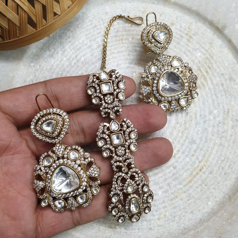 Pu&ograve; includere: Un set di orecchini e un anello per il naso dorati con pietre trasparenti. Gli orecchini hanno una forma a goccia e l'anello per il naso &egrave; piccolo e rotondo.