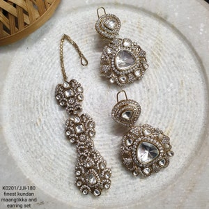 Heavy Kundan Polki Tikka Earring Set · CZ Bridal Jewelry Set · Sabyasachi Inspired Indian Wedding Set · Antique Gold Chandelier Earrings Maang Tikka, May include: A pair of gold-tone maang tikka and earring set featuring clear kundan stones. The maang tikka has a chain and three tiers of stones. The earrings are teardrop shaped with a large, clear kundan stone in the centre.