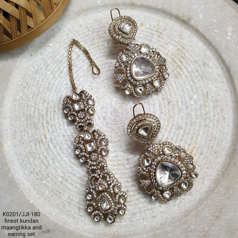Heavy Kundan Polki Tikka Earring Set · CZ Bridal Jewelry Set · Sabyasachi Inspired Indian Wedding Set · Antique Gold Chandelier Earrings Maang Tikka, May include: A pair of gold-tone maang tikka and earring set featuring clear kundan stones. The maang tikka has a chain and three tiers of stones. The earrings are teardrop shaped with a large, clear kundan stone in the centre.