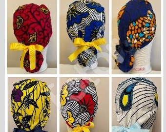 May include: Six different patterned surgical caps with ties. The caps are made of colorful fabric with various patterns, including floral, geometric, and abstract designs. The ties are yellow, blue, and white.