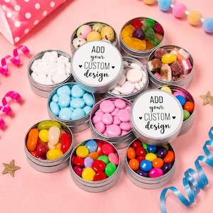May include: A collection of round silver metal tins filled with various colourful sweets, including jelly beans, chocolate-coated drops, and gummy candies. Two tins feature white circular labels with the black text ADD your CUSTOM design.