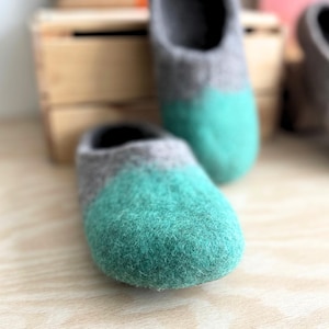 May include: A pair of gray and teal wool slippers. The slippers are soft and cozy, perfect for keeping your feet warm in the winter.