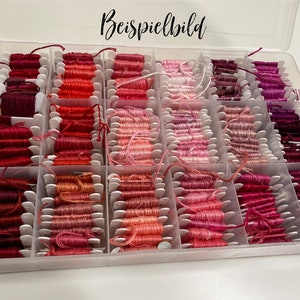 May include: A clear plastic organizer filled with spools of embroidery floss in various shades of red, pink, and purple. The floss is neatly arranged in individual compartments, with the text "Beispielbild" in the top center.